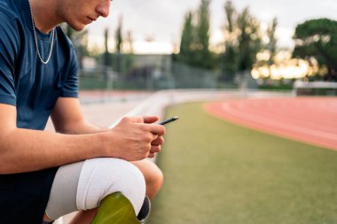 Disabled man athlete using his phone while doing a break.