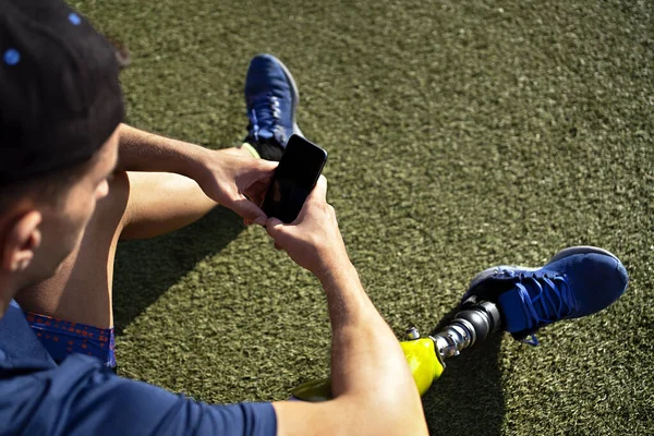 Disabled Man Athlete Using His Phone While Sitting Grass — Stockfoto