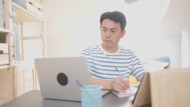 Відео Азіатського Дорослого Чоловіка Який Пише Нотатки Дивлячись Екран Ноутбука — стокове відео