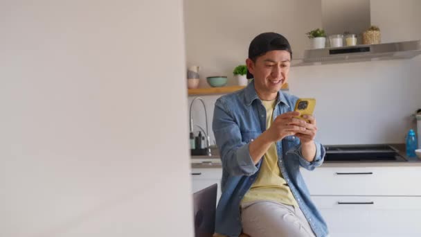 Video Chino Feliz Sentado Cocina Usando Móvil Sonriendo — Vídeo de stock