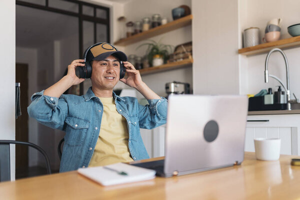 Happy Asian Casual Businessman Using Headphones While Working Home Royalty Free Stock Photos