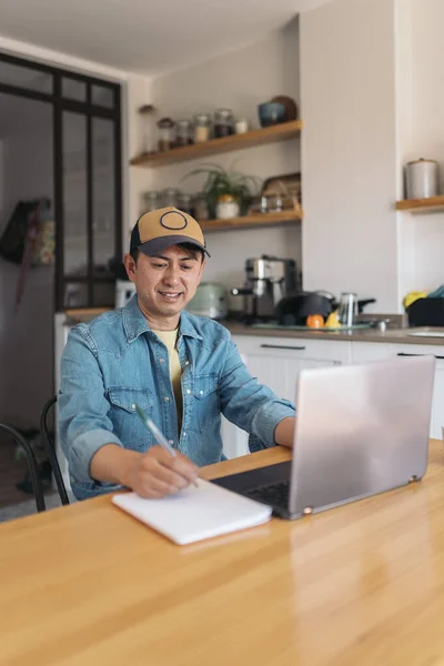 Vertikales Foto Eines Asiatischen Gelegenheitsunternehmers Mit Einem Laptop Während Notizen lizenzfreie Stockbilder