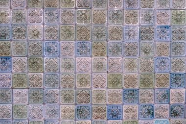 Duvarda kabartmalı renkli fayanslar var.