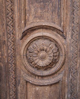 Rab, Croatia - 19 August, 2023: A circular ornamental wooden carving with concentric circles and intricate details on a natural, aged wood surface