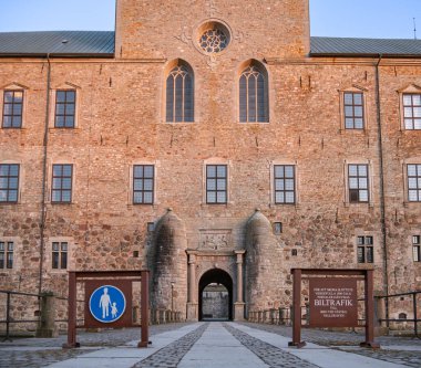 Vadstena, İsveç - 2 Nisan 2022: Vadstena 'daki ortaçağ şatosunun girişi, geçitin hemen ötesinde iki özel yarı dairesel sütun ile, üzerinde yayalar için tabelalar ve 