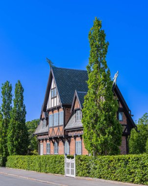 Kopenhag, Danimarka - 6 Haziran 2023: Danimarka 'da yemyeşil yeşilliklerle çevrili koyu renkli iki katlı tuğlalı bir ev.