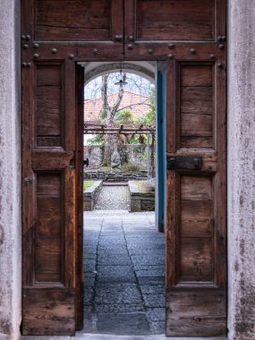 Kırsal ahşap bir kapı açılıyor ve bahçeye giden taştan bir yol açılıyor..