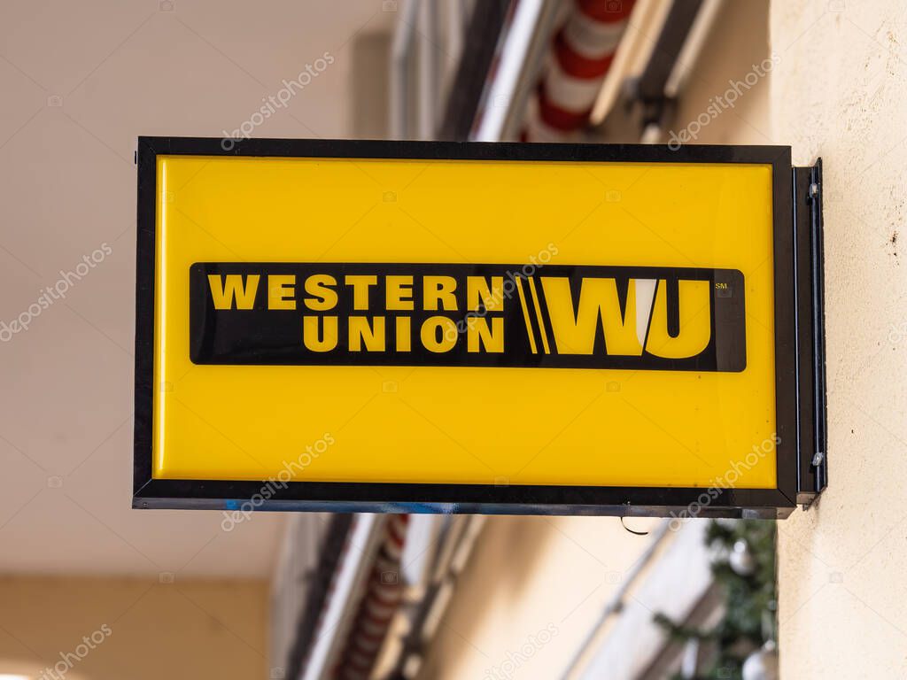 Locarno, Switzerland - 28 December 2021: A bright yellow Western Union sign with black text and logo, mounted on a building exterior.