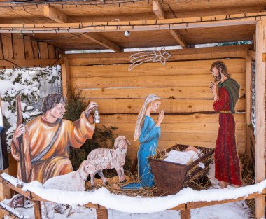 Cerknica, Slovenya - 4 Ocak 2025: Hayvanlarla çevrili bir ahırda Meryem, Yusuf ve İsa 'nın boyanmış figürlerinin olduğu ahşap bir doğum sahnesi