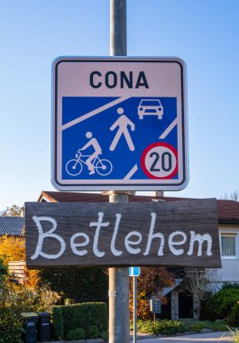 Domzale, Slovenya - 29 Ekim 2024: Bir yerleşim bölgesinde 20 hız sınırına sahip yaya ve bisiklet bölgesini gösteren bir tabela. Altında beyaz boyayla yazılmış 'Betlehem' yazan tahta bir tabela var..