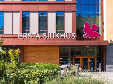 Stockholm, İsveç - 11 Mayıs 2025: 'Ersta Sjukhus' isminin yer aldığı modern bir hastane binası cephesi Girişte yeşillik ve büyük pembe bir güvercin logosu var..