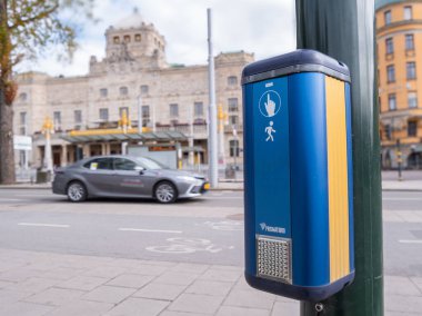 Stockholm, İsveç - 11 Mayıs 2025: Bulanık bir araba ve arka planda tarihi binalar bulunan bir caddede yaya geçidi sinyal kutusu.
