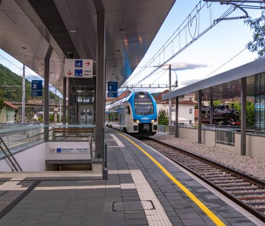 Güneşli bir günde mavi beyaz trenli modern tren istasyonu.
