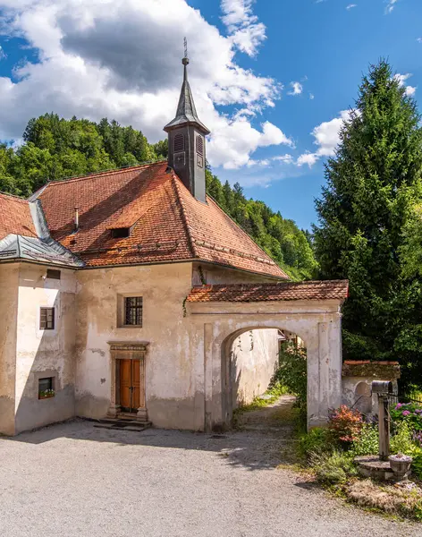 Skofja Loka, Slovenya - 17 Temmuz 2025: Dik kırmızı çatılı AA büyüleyici eski bina ve çan kulesi. Bina ve şapel, Skofja Loka 'daki müzik okulunun ev sahipliği yaptığı yer..