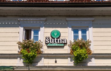 Kamnik, Slovenya - 10 Ağustos 2025: Pasta dükkanı ve çiçek kutuları için tabelası olan bir binanın cephesi.