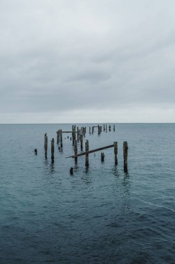 Derelict pier off the Jurrasic coast in the UK. Cold sea water and grey clouds. Copy space available