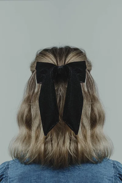 Back of young womans head showing blonde brow hair against white background. Copy space available.