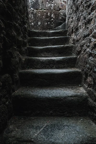 stock image A mysterious staircase winding up a dark wall, illuminated by the shadows of built structures. It beckons to explore the way forward. Portrait orientation with copy space