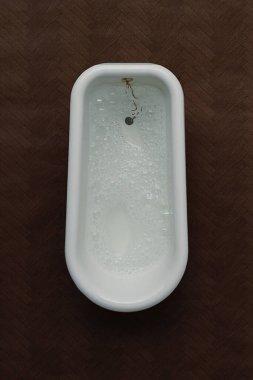 Geleneksel beyaz banyo sahnesi yukarıdan, koyu ahşap arka planda. Kopya alanı ile portre yönelimi