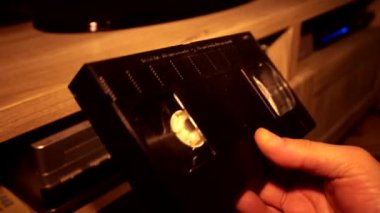 Adamın elinde bir VHS kaseti var. Düşük ışık.