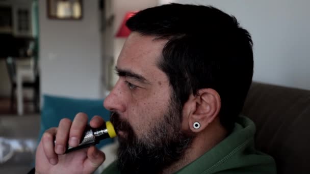 Мужчина Бородой Сидит Дома Диване Курит Электронную Сигарету — стоковое видео