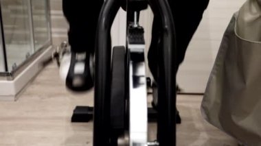 Güzellik merkezinde egzersiz bisikletinde pedal çeviren bir kız..