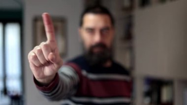 Sakallı adam ciddi bir ifadeyle evde parmaklarıyla hayır diyor..