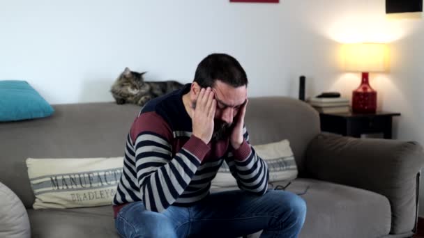 自宅のリビングルームでソファーに座っているストレスのひげ付き男 — ストック動画