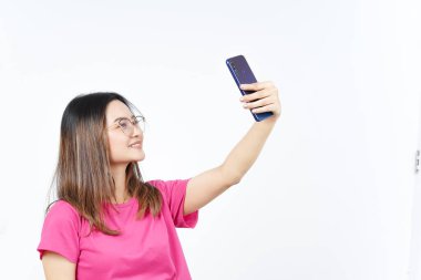 Beyaz arka planda izole edilmiş güzel Asyalı kadının akıllı telefonuyla bir selfie çek.