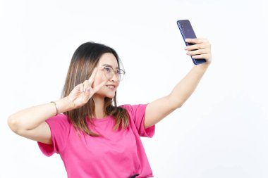 Beyaz arka planda izole edilmiş güzel Asyalı kadının akıllı telefonuyla bir selfie çek.