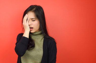 Kızıl arka planda tecrit edilmiş güzel bir Asyalı kadının baş ağrısı.