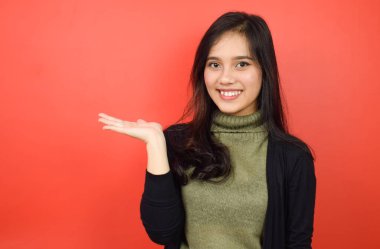 Kırmızı arka planda izole edilmiş güzel bir Asyalı kadının açık avucundaki ürünleri gösterme ve sunma