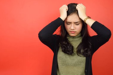 Kızıl arka planda tecrit edilmiş güzel bir Asyalı kadının baş ağrısı.