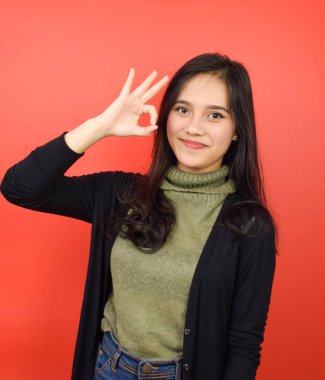 Kırmızı Arkaplanda İzole Edilmiş Güzel Asyalı Kadın 'ın Tamam İşareti ve gülümsemesi