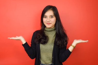 Kırmızı arka planda izole edilmiş güzel bir Asyalı kadının açık avucundaki ürünleri gösterme ve sunma