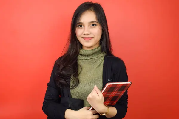 Elinde Kitap Gülücükle Kızıl Arkaplanda Tecrit Edilmiş Güzel Bir Asyalı — Stok fotoğraf