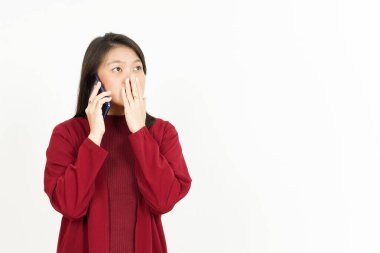 Şok olmuş kırmızı tişörtlü güzel Asyalı kadın yüzüyle bir telefon görüşmesi yap.