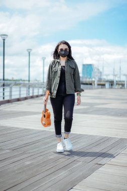 Ceket ve açık havada siyah kot giyen güzel bir Asyalı kadının Ukulele 'sini oynuyorum.