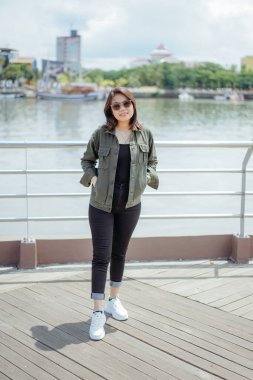 Ceket ve siyah kot giyen, dışarıda poz veren güzel bir Asyalı kadın.