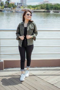 Ceket ve siyah kot giyen, dışarıda poz veren güzel bir Asyalı kadın.