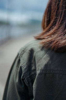 Ceket ve siyah kot giyen, dışarıda poz veren güzel bir Asyalı kadın.