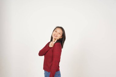 Kırmızı tişörtlü genç Asyalı kadın gülümsüyor ve beyaz arka planda izole edilmiş barış ya da zafer işareti gösteriyor.