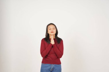 Kırmızı tişörtlü genç Asyalı kadın gözlerini kapatıp beyaz arka planda tek başına dua ediyor.