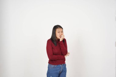 Genç Asyalı kadın korkuyor ve beyaz arka planda kırmızı tişört giyen tırnak yiyor.