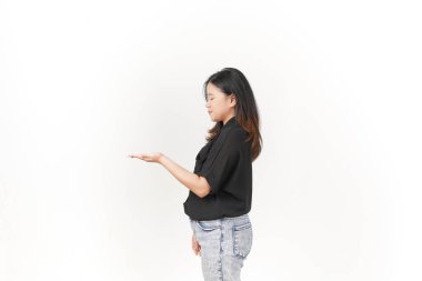 Beyaz arka planda siyah tişört ve kot pantolon giyen Asyalı genç bir kadın açık avuç içi fotokopi alanında ürününü gösteriyor.