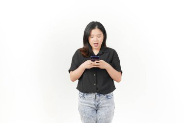 Siyah tişört ve beyaz arka planda izole edilmiş kot pantolon giyen Asyalı genç kadın Tutma ve Akıllı Telefon, Mesajlaşma veya Sohbet Konsepti