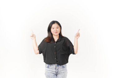 Ürün gösteren ve fotokopi alanını gösteren genç Asyalı kadın beyaz arka planda siyah tişört ve kot pantolon giyiyor.