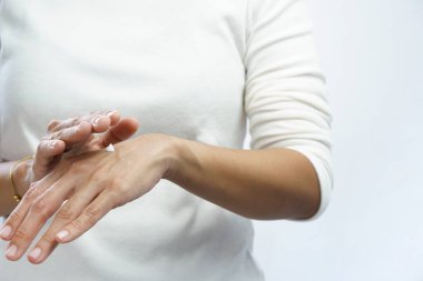 Kadın ellerinin üzerine krem sürüyor.