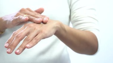 Kadın ellerinin üzerine krem sürüyor.