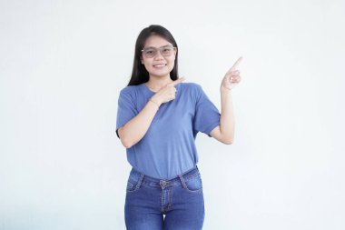 Güzel Asyalı kadın yan fotokopi alanına işaret ederken gülümsüyor, beyaz arka planda reklam veya promosyonlar için mükemmel.